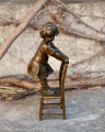Bronzová soch holčičky v šatech na stoličce