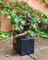 Bronzová socha polonahá sedící dívka